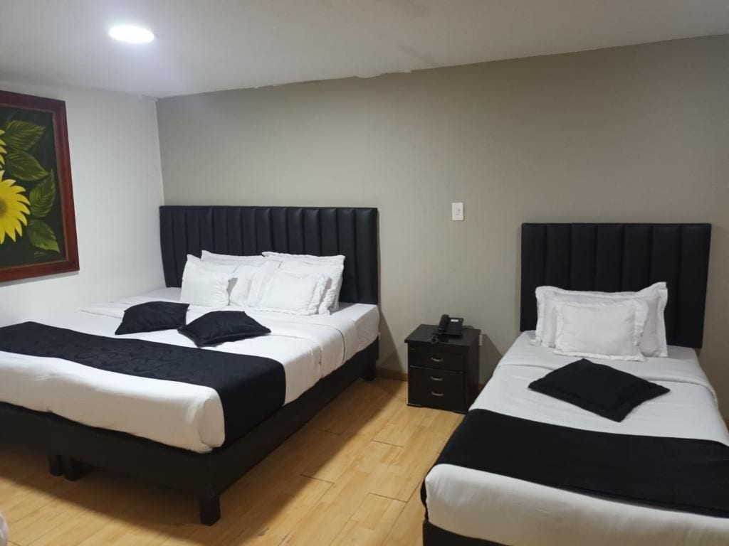 A hotel room with two beds, a nightstand, and a painting on the wall.