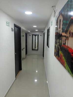 Un couloir avec des portes, un sol carrelé et un tableau accroché au mur.