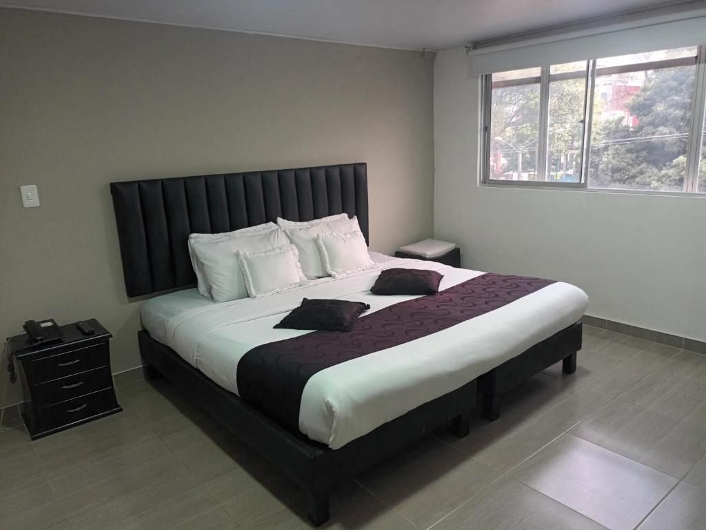 A bedroom with a bed, bedside tables, a nightstand, and a window.