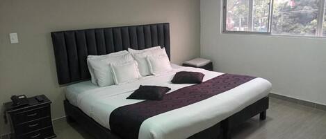 A bedroom with a bed, bedside tables, a nightstand, and a window.