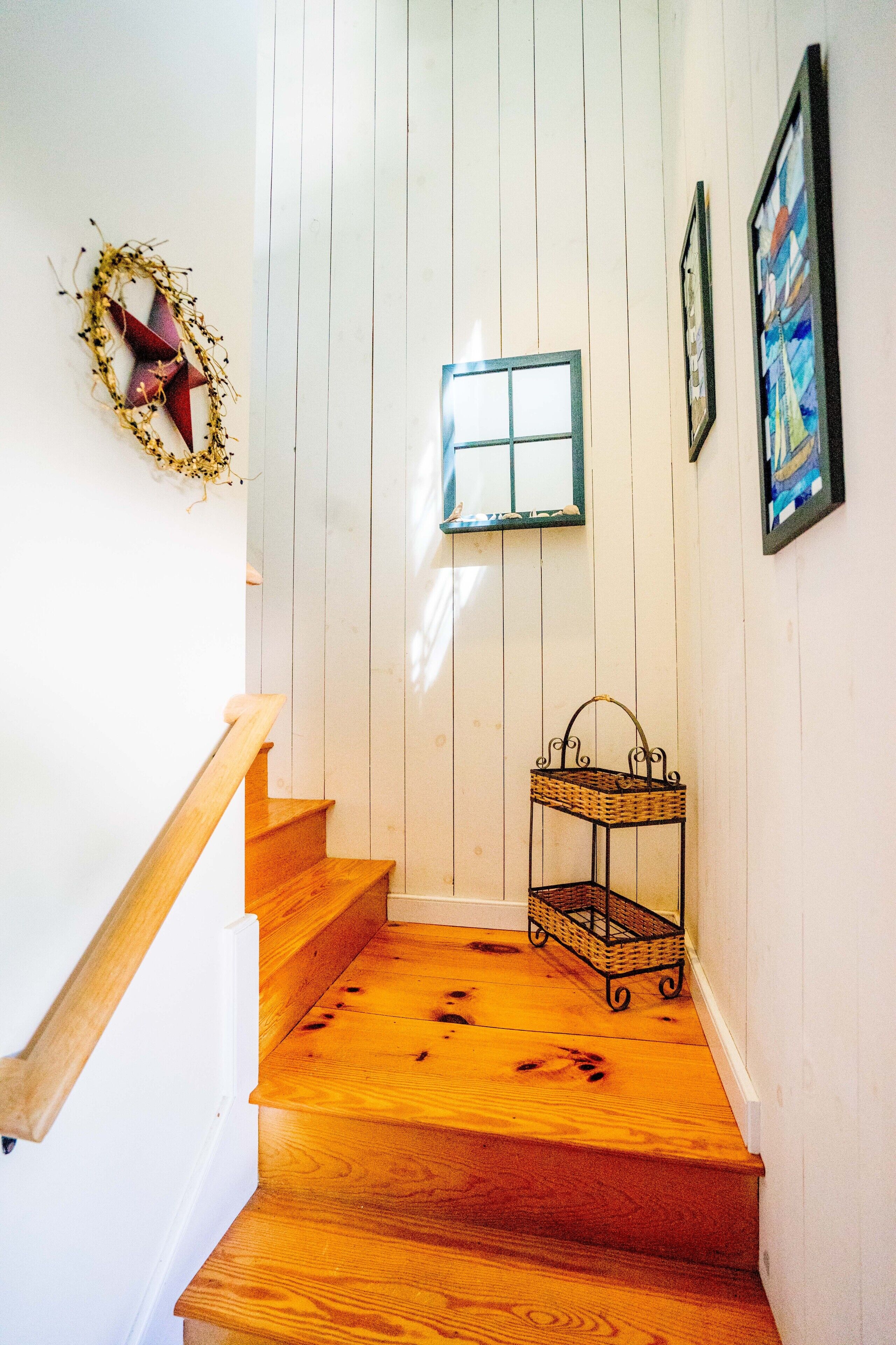 A wooden staircase with a white wall and a small window.