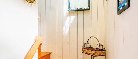 A wooden staircase with a white wall and a small window.