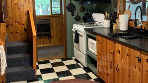 A kitchen with wooden cabinets, a stove, a sink, and a checkered floor. - Waterfront Lakefront Cottage, Sleeps 6. Parking.  (Old Town)