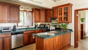 A kitchen with wooden cabinets, a central island, a dishwasher, a microwave, and a coffee maker.