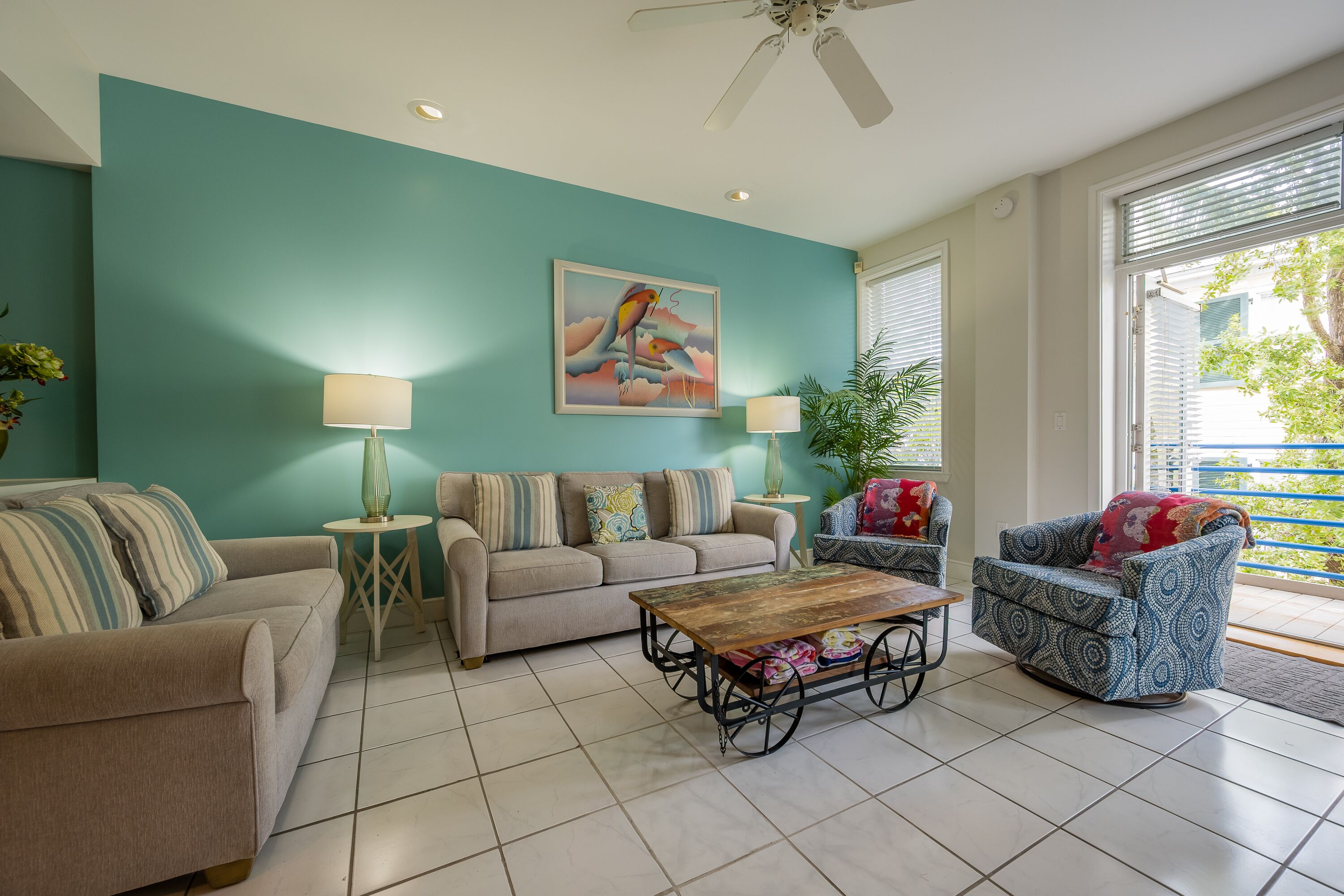 A living room with teal walls, a ceiling fan, a wooden coffee table, and two sofas.