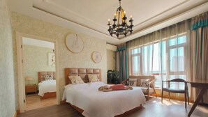 A spacious bedroom with a large bed, a wooden floor, a chandelier, and a view of the city through large windows. - Dalian Bo Ke Business Apartment (Dalian)