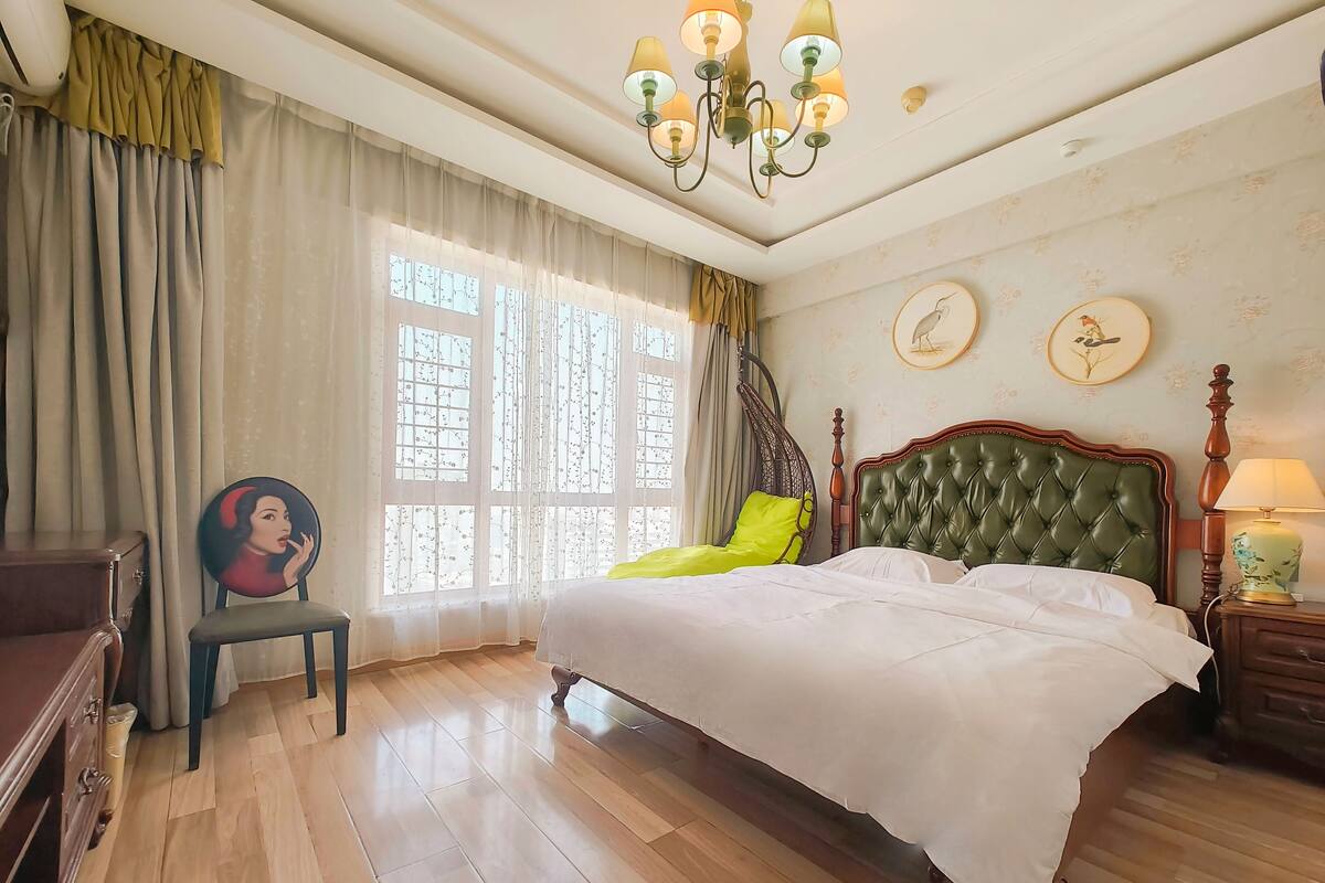 Ein Schlafzimmer mit einem großen Bett, einer Holzkommode, einem Stuhl und einem Hängesessel.