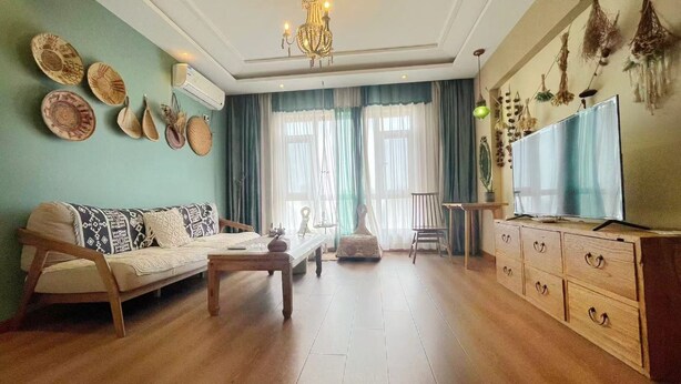 A living room with a sofa, coffee table, TV, and decorative items on the wall. - Dalian Bo Ke Business Apartment (Dalian)