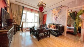 A traditional room with a wooden floor, a sofa set, a dining table, and a television. - Dalian Bo Ke Business Apartment (Dalian)