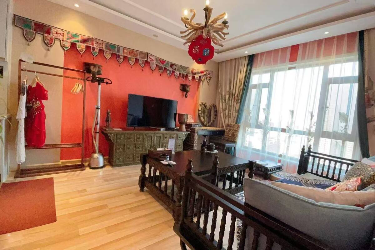 Ein Wohnzimmer mit Fernseher, Essbereich mit Tisch und Stühlen, Sofa und einem großen Fenster mit Vorhängen.