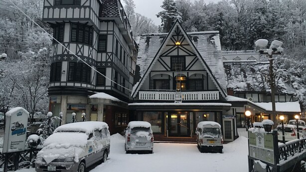 Un edificio tradicional de entramado de madera con techo empinado, una torre central y una entrada cubierta de nieve.