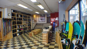 Una habitación con suelo a cuadros, muebles de madera y estantes con esquíes y tablas de snowboard.