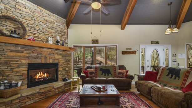 A cozy living room with a stone fireplace, a large window, and a comfortable couch. - WOW‼️CREEKSIDE 3KINGS-Sleeps 10 🐩🐕Dogs🫶 Near DTown,Orchard,Rivers,Vineyard,Hiking (Blue Ridge)