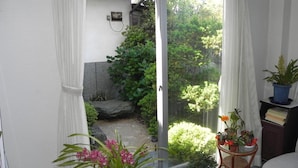 Ein Balkon mit Blick auf einen Garten, ein kleiner Tisch mit einer Pflanze und ein Stuhl.