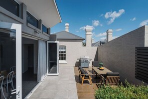 Een modern huis met een patio, inclusief een barbecue, zitplaatsen buiten en uitzicht op de omgeving.