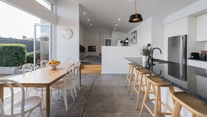 Una cocina moderna con una isla central, electrodomésticos de acero inoxidable y un comedor con mesa y sillas de madera.
