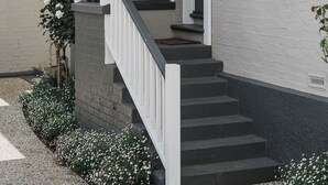 Una casa con fachada blanca, un porche con barandilla y una escalera que conduce a la entrada.