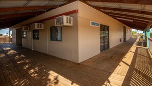 A reception area with a sign, air conditioning units, and a covered wooden deck. - Longreach Outback Adventures (Longreach)