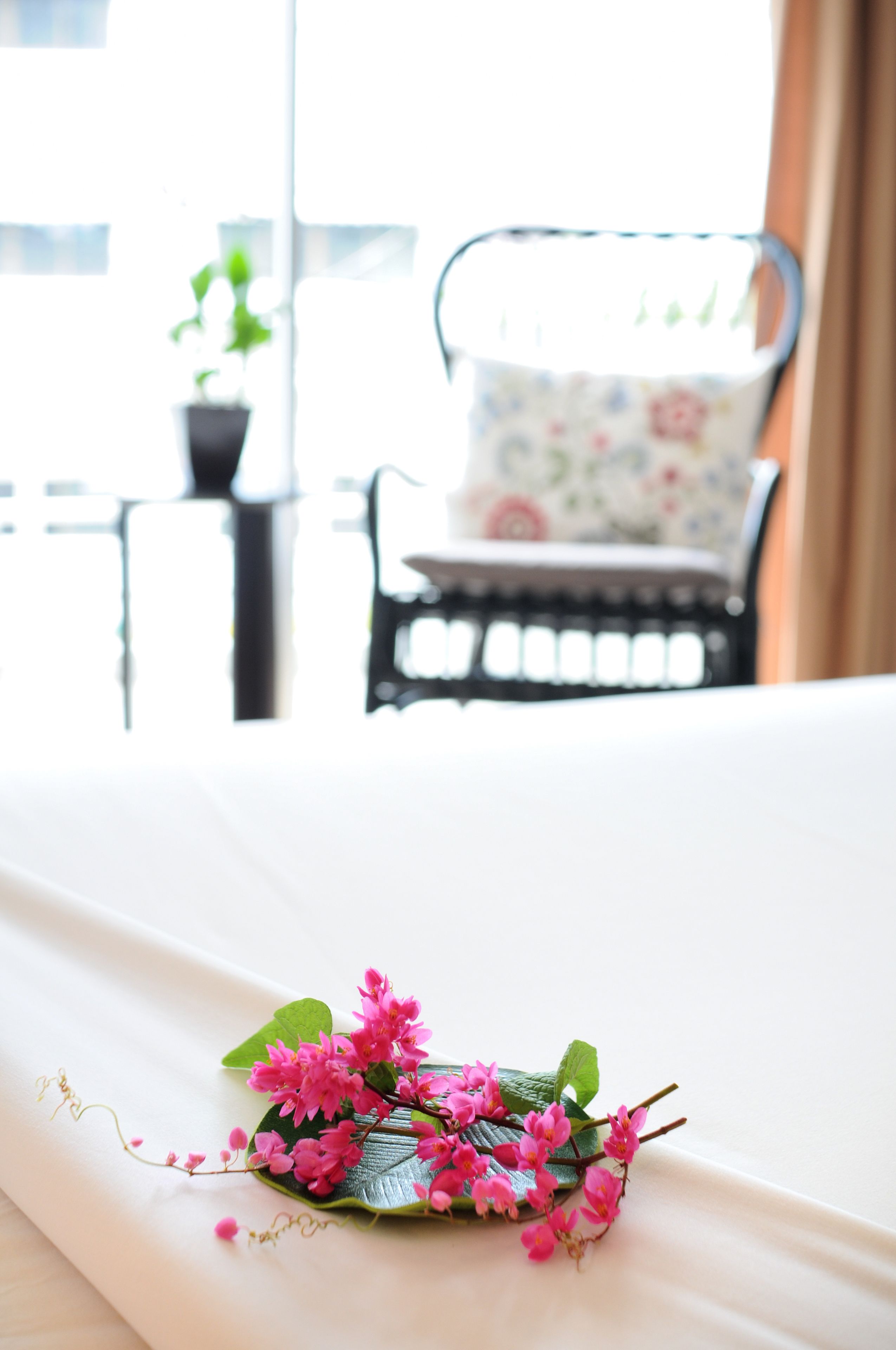 A bed with a white sheet and a floral arrangement on it.