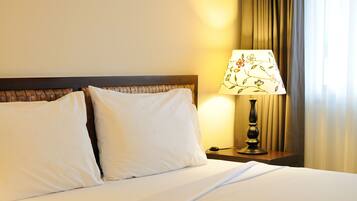 A neatly made bed with white linens, a wooden headboard, and a bedside table with a lamp.
