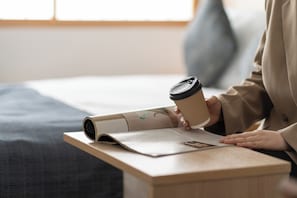 A person reading a newspaper with a coffee cup on a wooden table. - Hotel Vista Premio Kyoto Nagomitei (Kyoto)