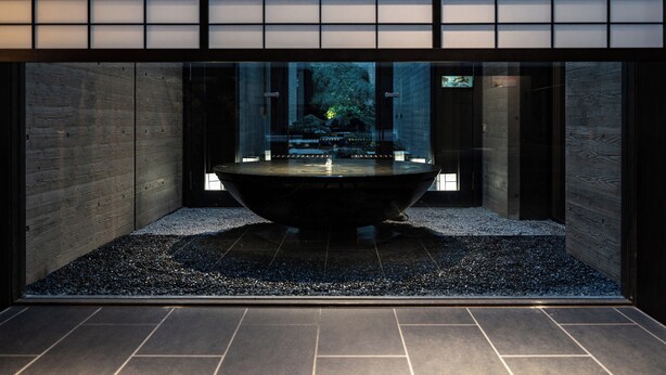 A modern interior with a central water feature, wooden walls, and a tiled floor.