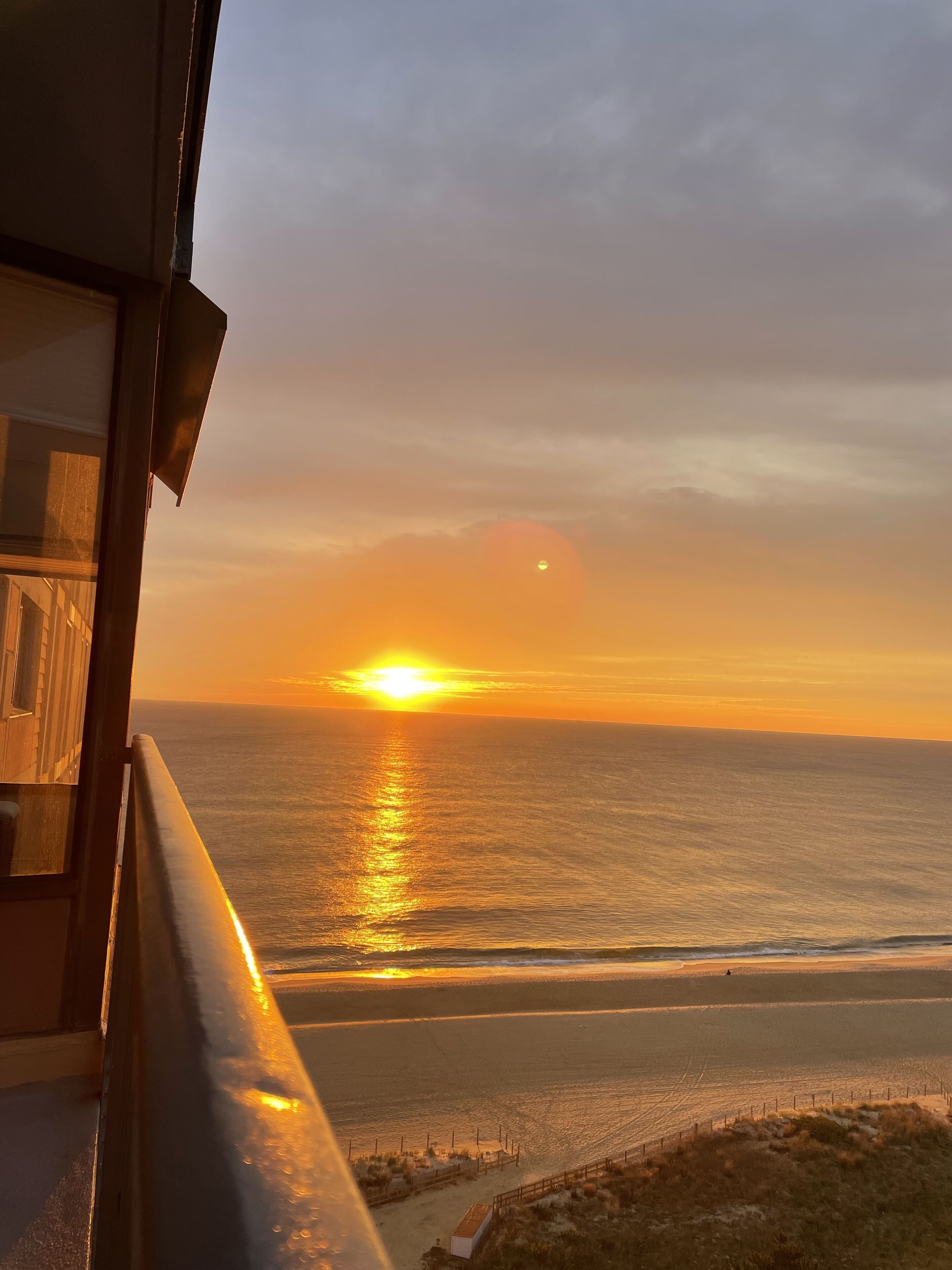 Un coucher de soleil sur l’océan, vu depuis un balcon doté d’une balustrade.
