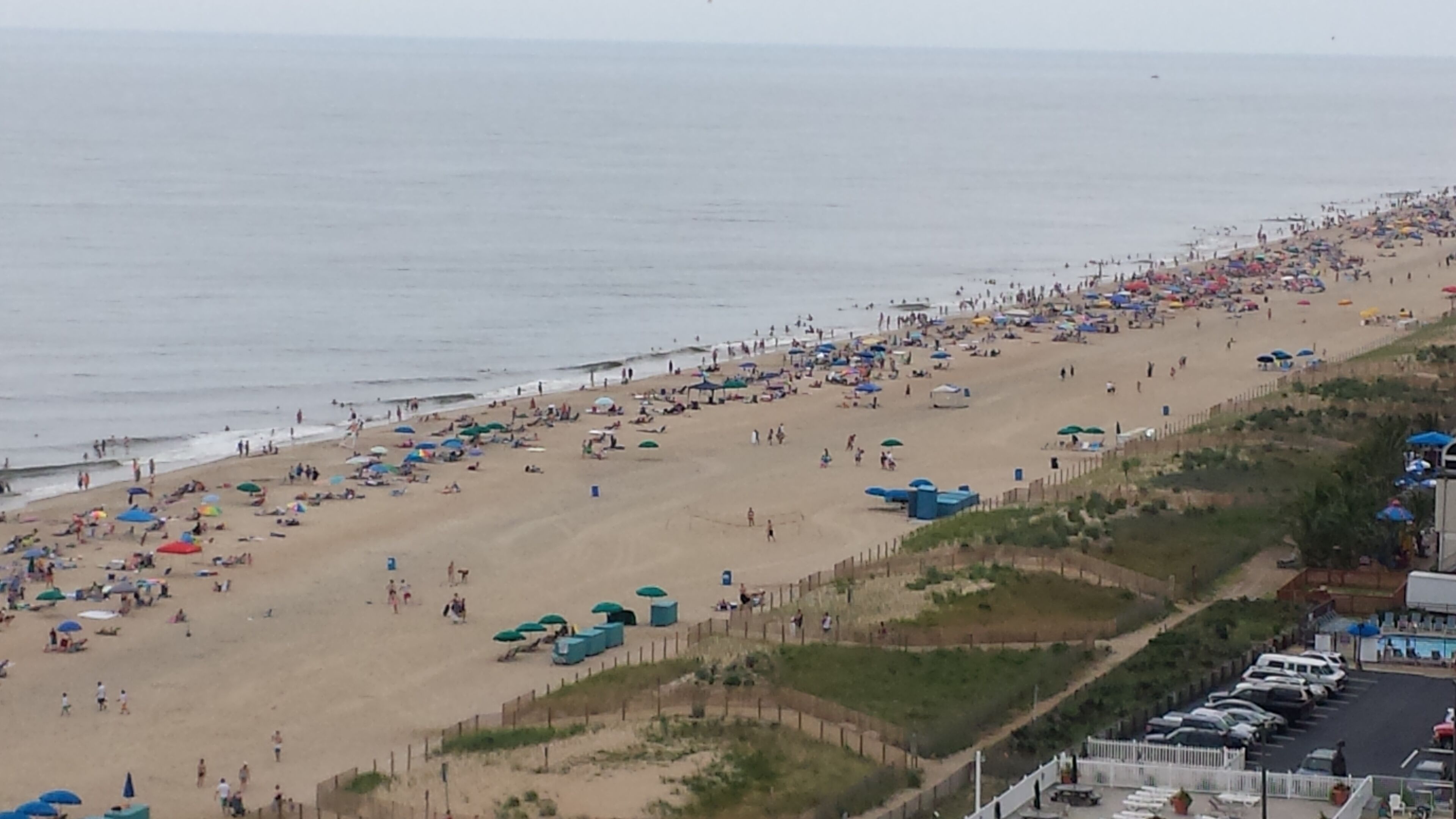 Ein Strand mit vielen Sonnenschirmen und Personen.