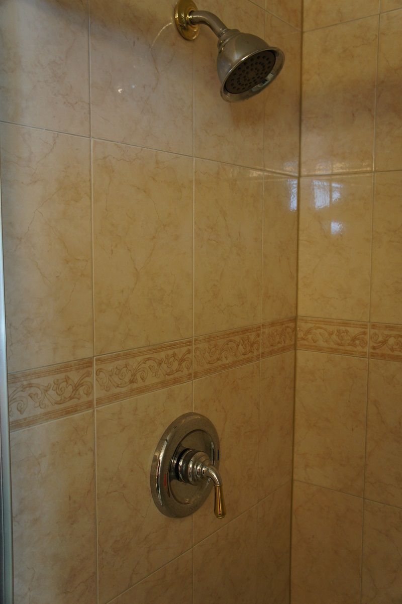 A shower with a handheld showerhead and a wall-mounted faucet.