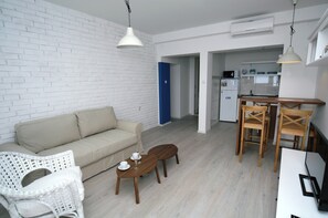 Uma sala de estar moderna com um sofá, uma mesa de centro e um espaço de jantar com cadeiras e uma mesa.