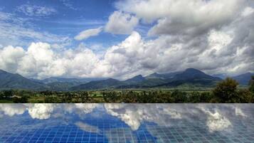 An infinity pool with a clear view of mountains and a cloudy sky.