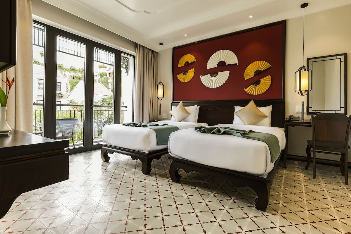 Una habitación de hotel con dos camas, un ventanal grande y un adorno de pared decorativo.