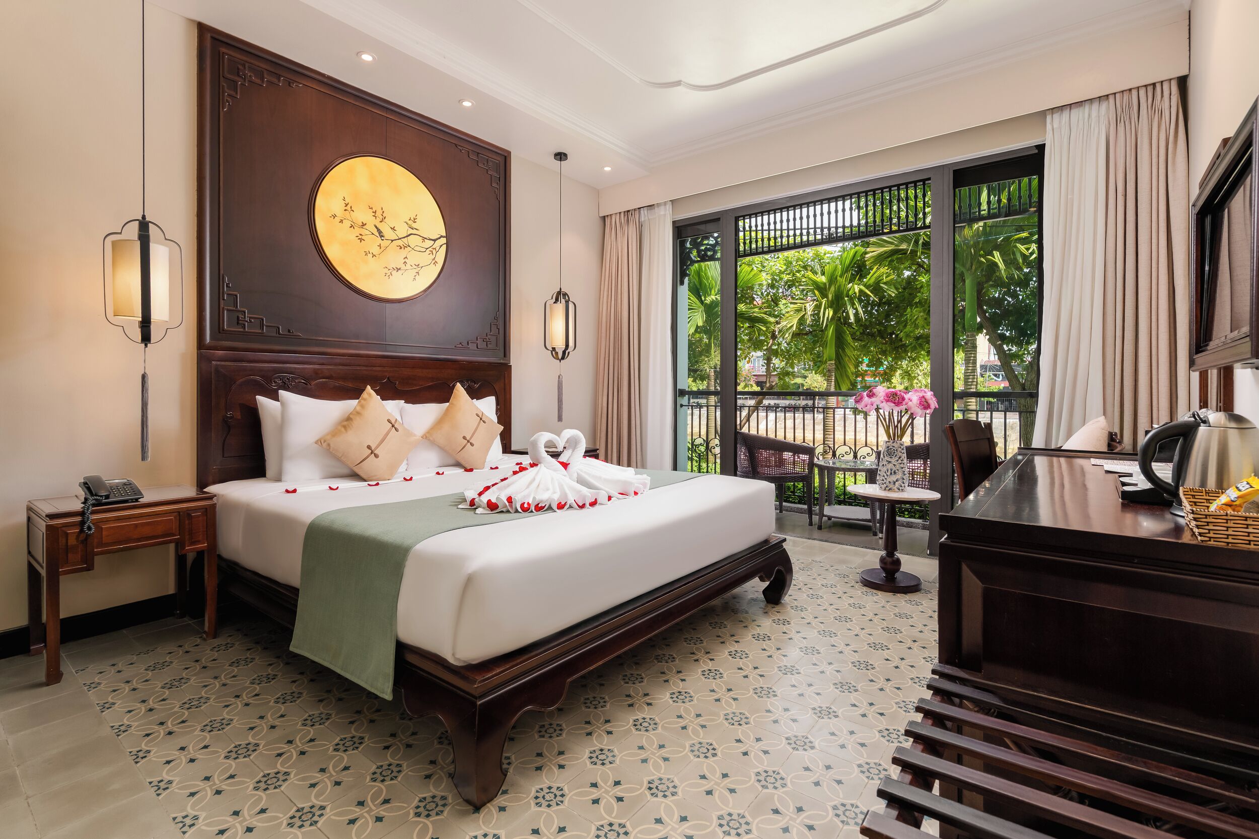 Une chambre d’hôtel avec un grand lit, un bureau, une chaise, une petite table et une vue sur l’extérieur.