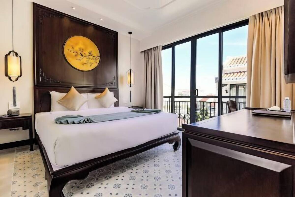 Habitación de hotel con una cama grande, un escritorio, vistas de la ciudad y un adorno de pared.