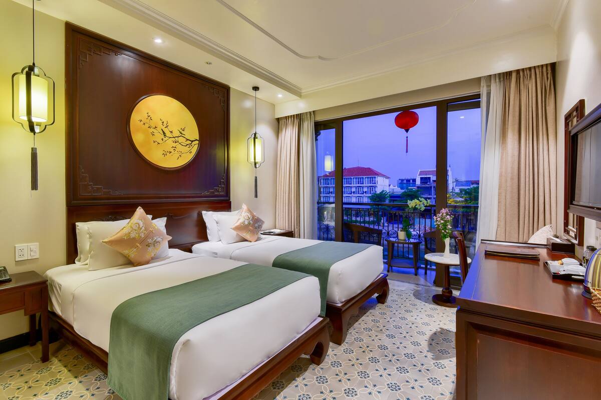 Habitación de hotel con dos camas, un balcón con vistas y una decoración grande en la pared.