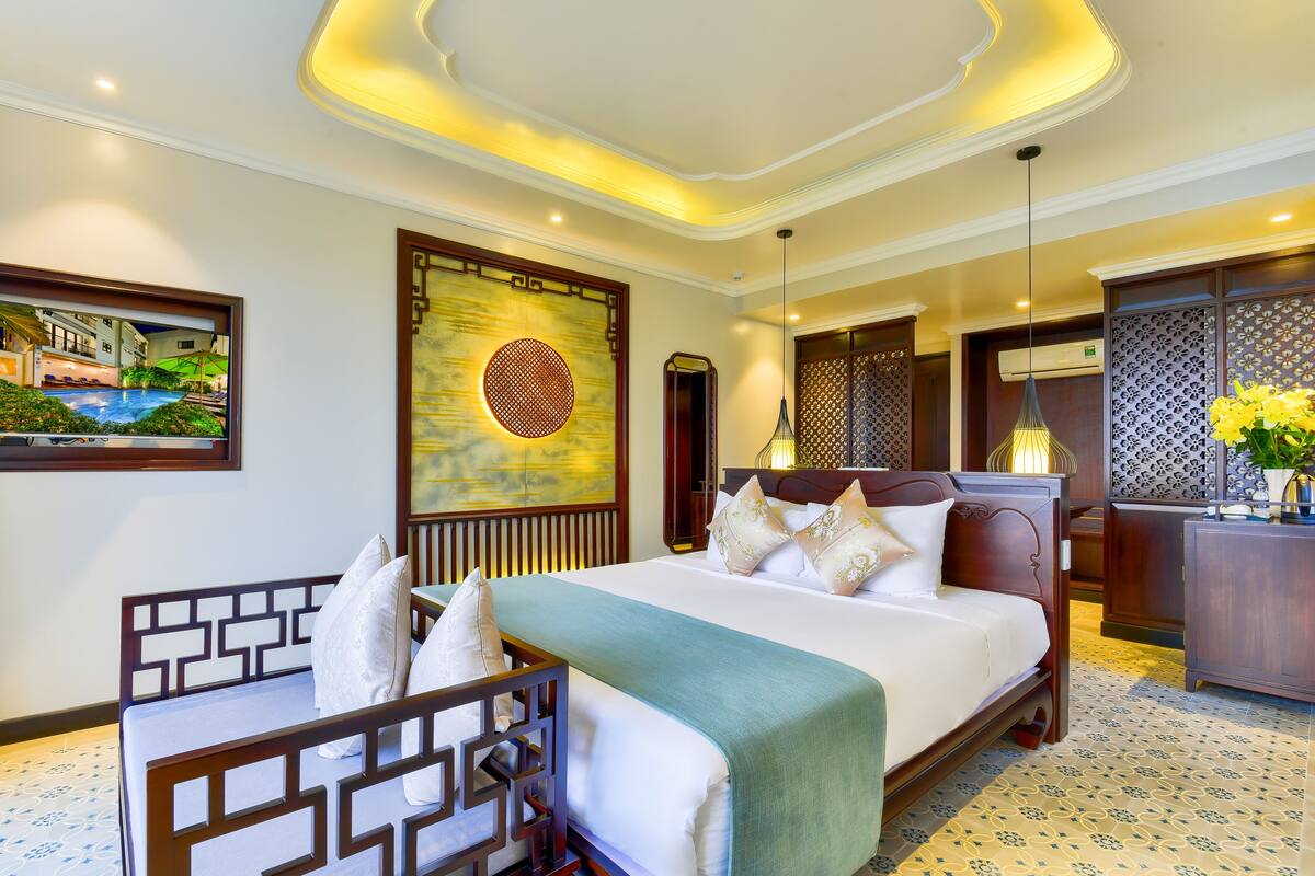 Una habitación de hotel con una cama grande, un escritorio, una silla, una pared decorativa y un cuadro de un paisaje.