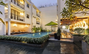Una piscina al aire libre, sombrillas, sillones reclinables de piscina
