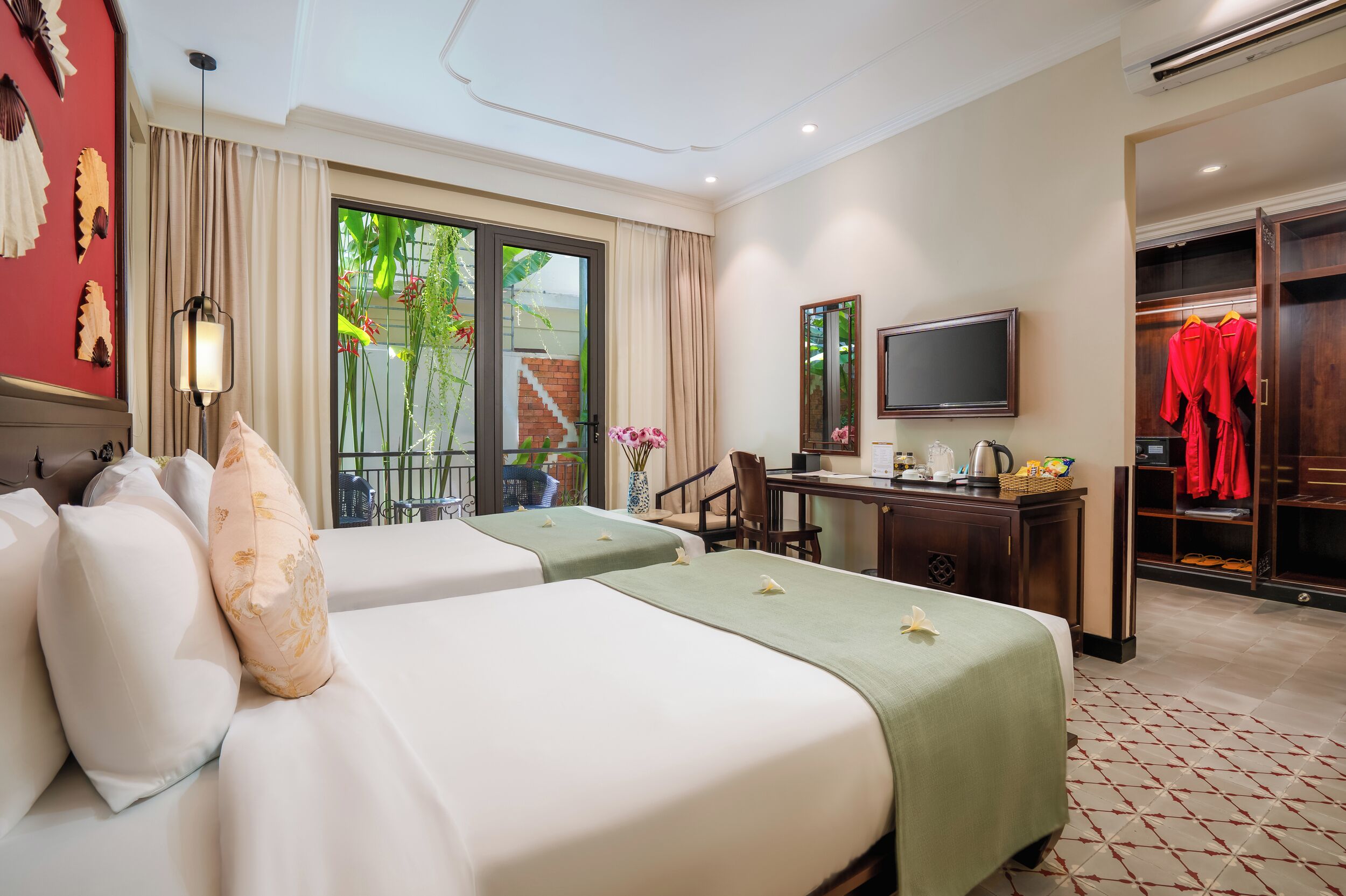 A hotel room with two beds, a desk with a chair, a TV, and a wardrobe.