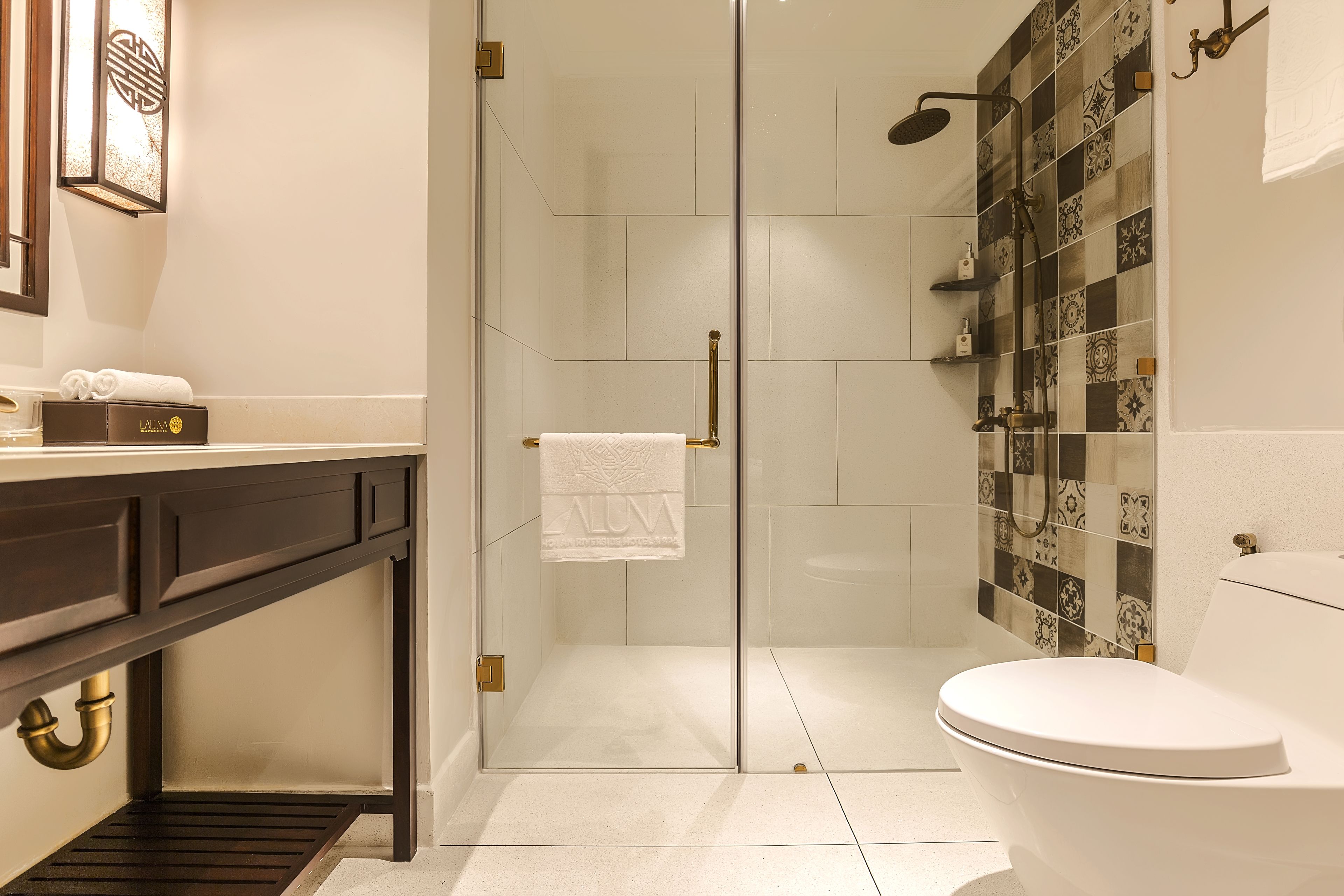 A modern bathroom with a glass-enclosed shower, a white toilet, and a vanity with a dark countertop.