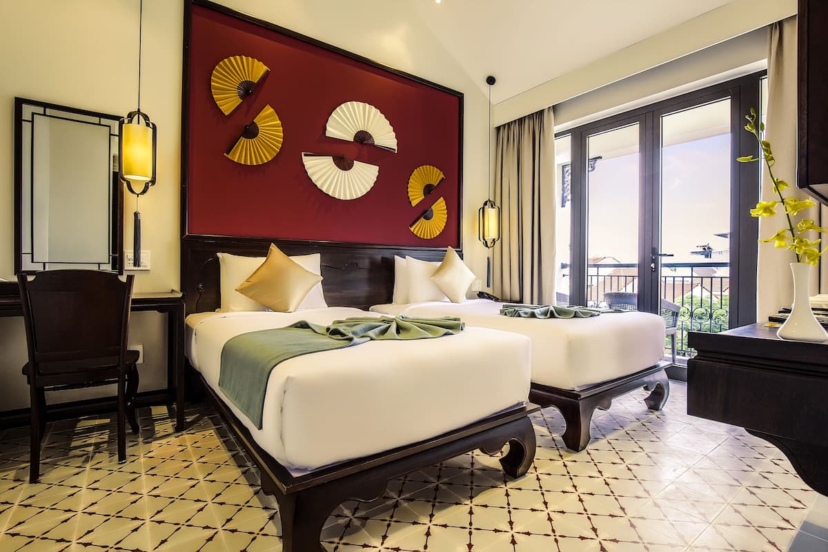 Habitación de hotel con cama, dos mesitas de noche, una silla, escritorio y un ventanal con vistas.