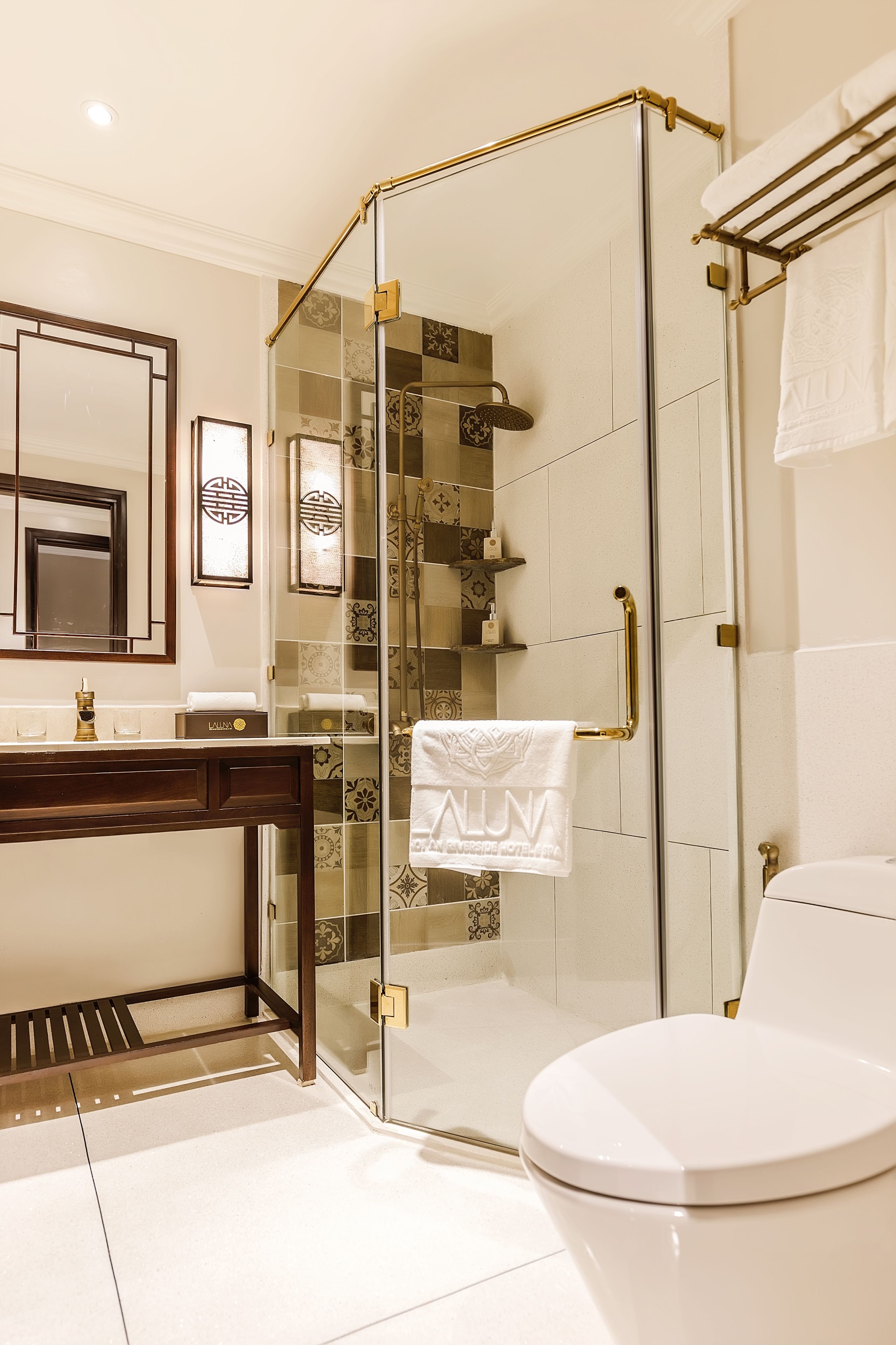 A modern bathroom with a glass-enclosed shower, a white toilet, a vanity with a mirror, and a towel rack.