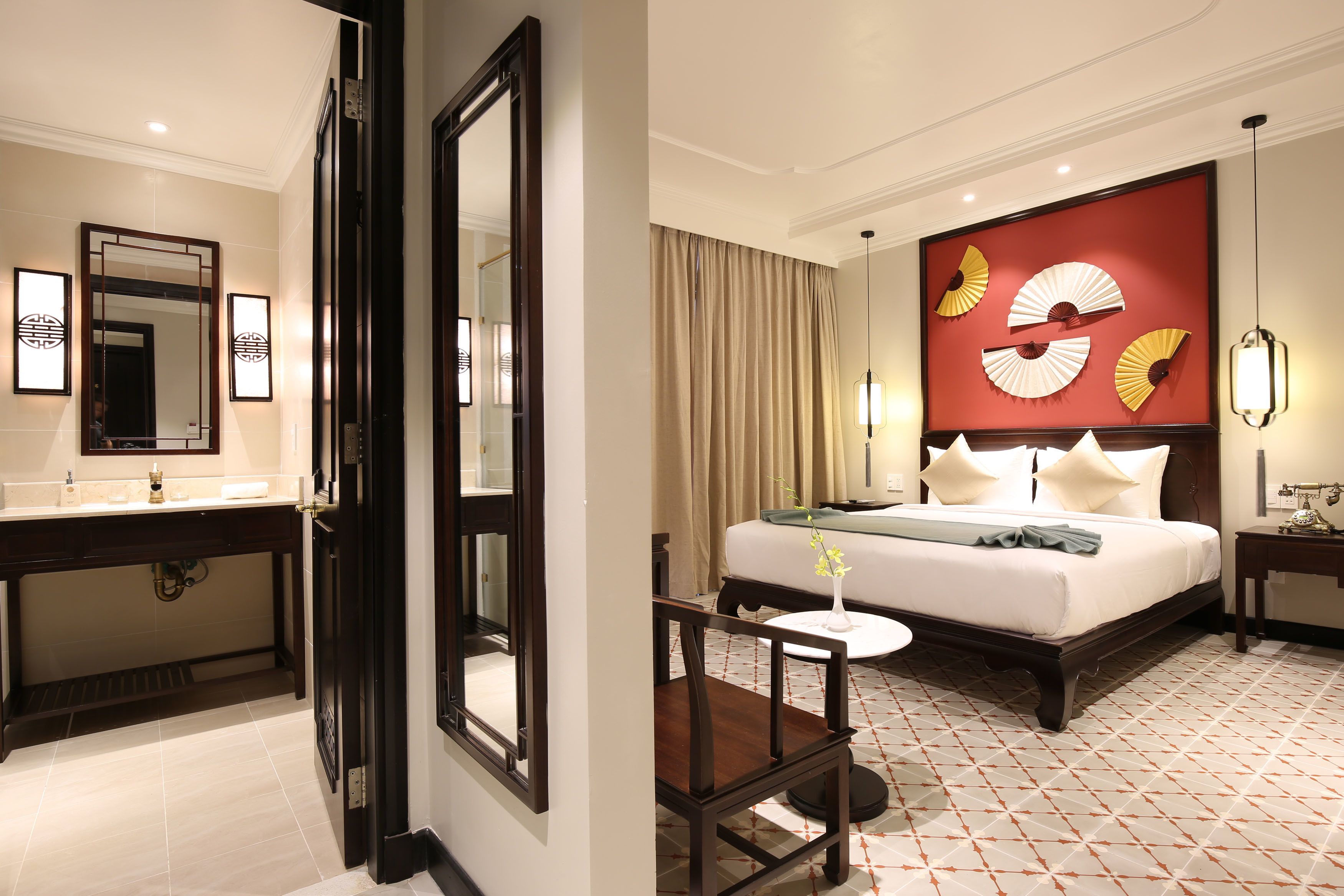 A hotel room with a bed, bedside table, and a mirror.