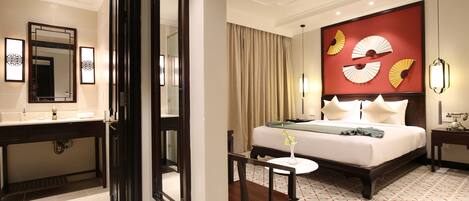 A hotel room with a bed, bedside table, and a mirror.