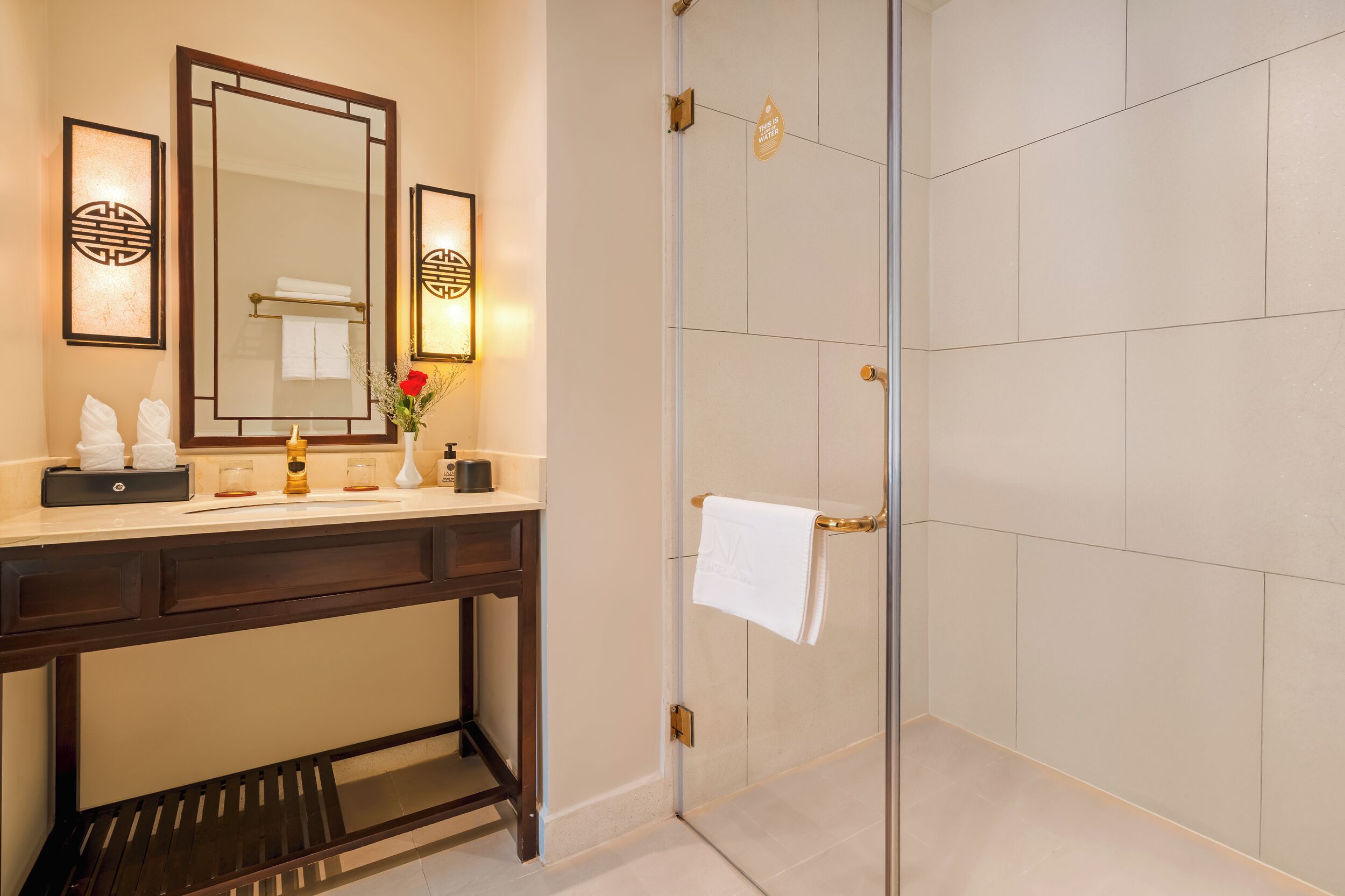 A bathroom with a vanity, mirror, towel rack, and shower area.
