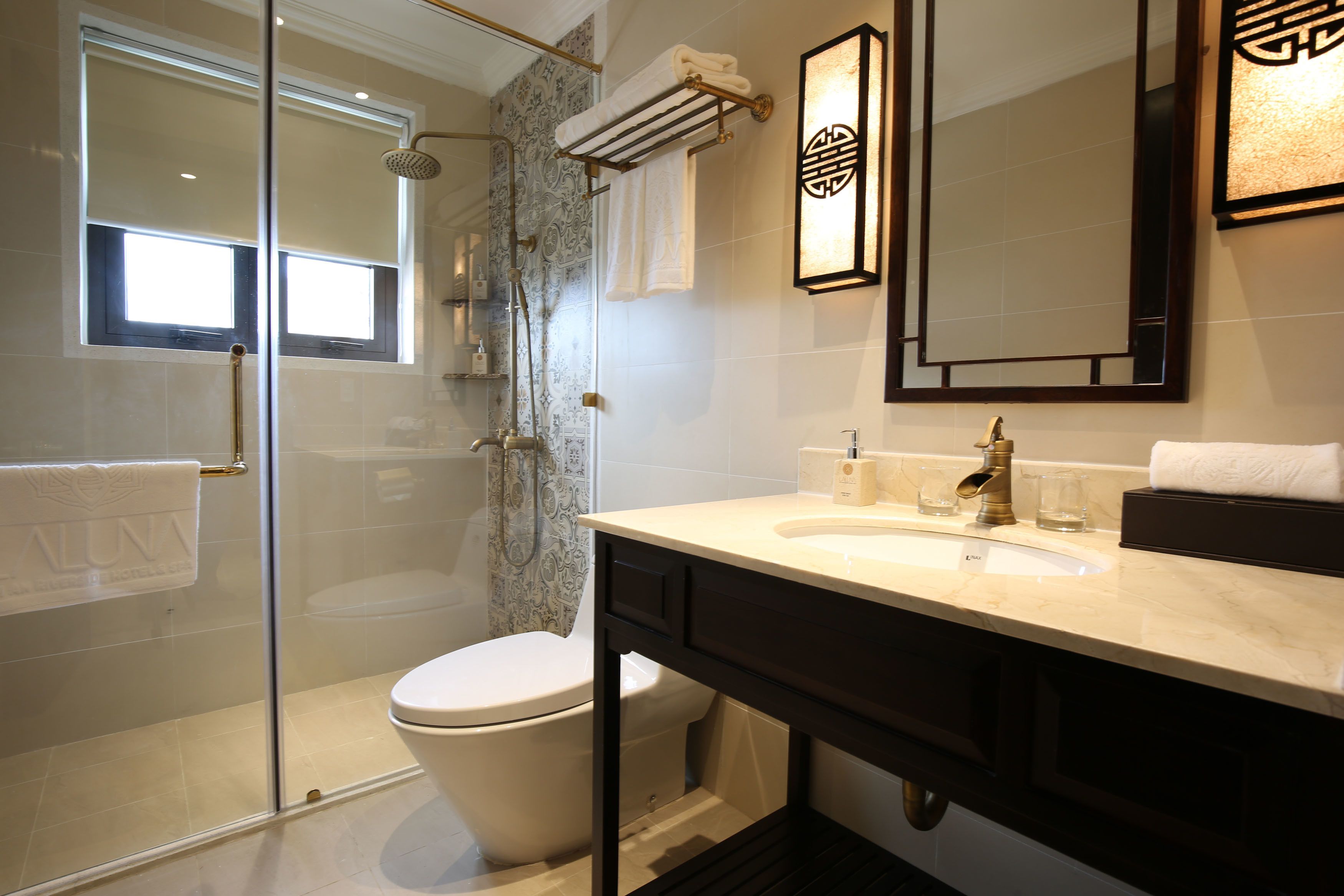 A modern bathroom with a glass-enclosed shower, a toilet, and a vanity with a sink and mirror.