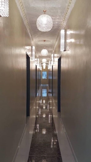Un pasillo largo y estrecho con suelo reflectante y múltiples lámparas esféricas.