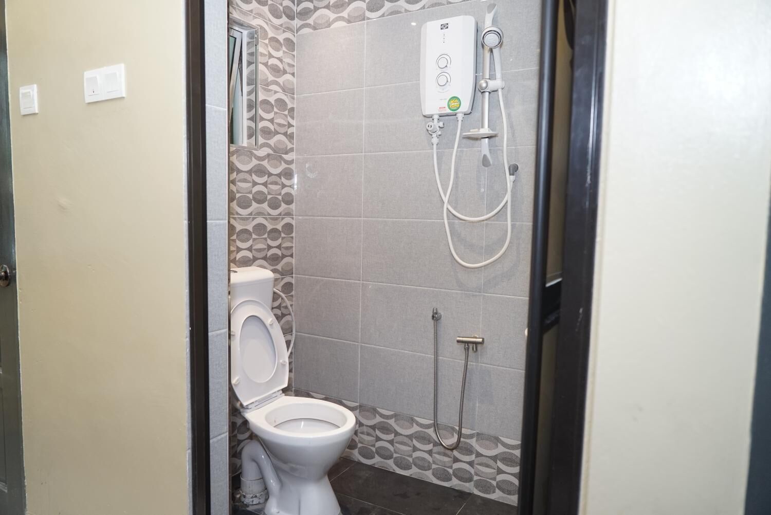 A small bathroom with a toilet, a shower, and a wall-mounted water heater.