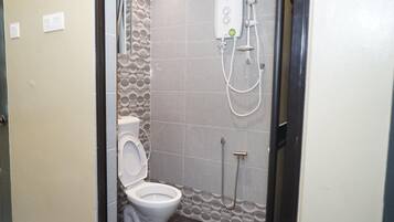 A small bathroom with a toilet, a shower, and a wall-mounted water heater.