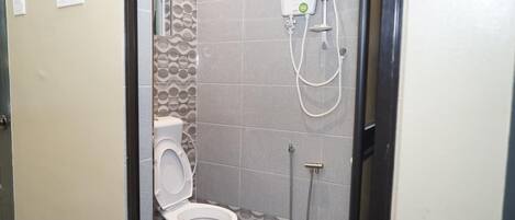 A small bathroom with a toilet, a shower, and a wall-mounted water heater.