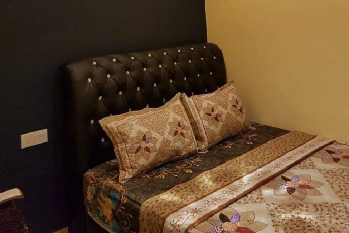 A bedroom with a dark headboard, a patterned bedspread, and a unique spherical light fixture.